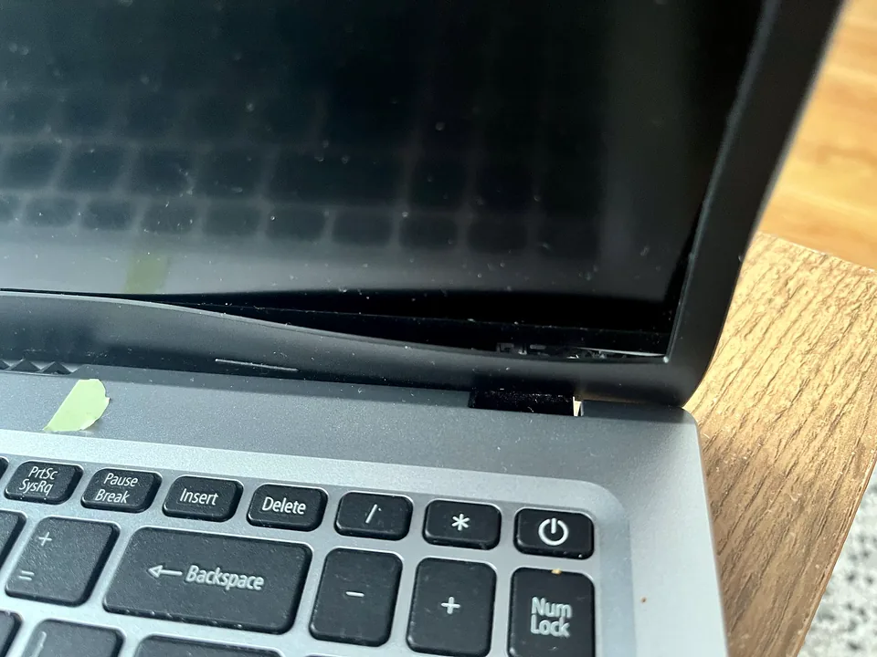 Laptop hinge repairs Broken laptop hinge and screen casing being inspected before repair